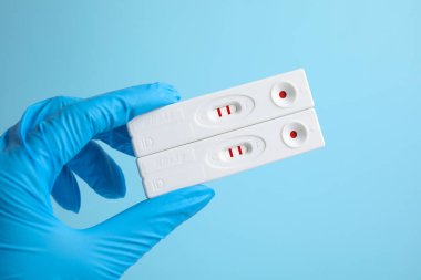 Doktor açık mavi arka planda hepatit için iki adet kullan at ekspres test tutuyor.