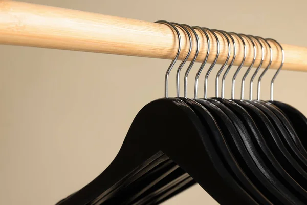 Black Clothes Hangers Wooden Rail Beige Background Closeup — Stockfoto