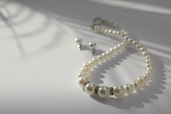 精致的珍珠项链和耳环放在白桌上 案文的篇幅 — 图库照片