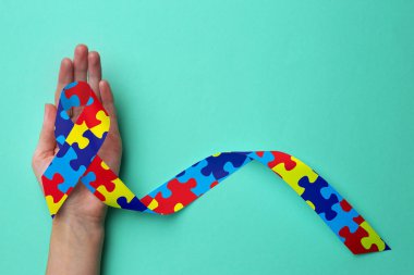 Dünya Otizm Farkındalık Günü. Cyan arka planda renkli yapboz kurdelesi olan kadın, üst görünüm