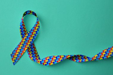 Dünya Otizm Farkındalık Günü. Cyan arkaplanda renkli bulmaca kurdelesi, üst görünüm
