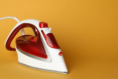 Turuncu arka planda modern bir ütü, metin için boşluk. Ev aletleri
