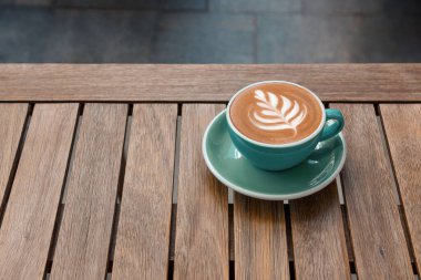 Dışarıdaki ahşap masada bir fincan aromatik sıcak kahve, metin için yer.