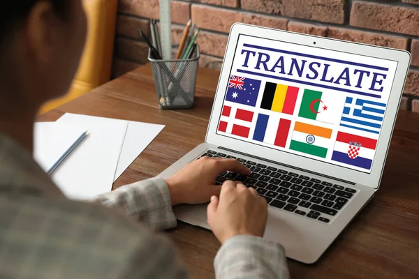 Çevirici Masadaki Farklı Bayrakların Görüntülerini Içeren Modern Dizüstü Bilgisayar Kullanıyor — Stok fotoğraf