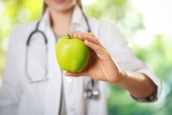 Dietetyk Świeżym Jabłkiem Rozmazanym Zielonym Tle Zbliżenie — Zdjęcie stockowe