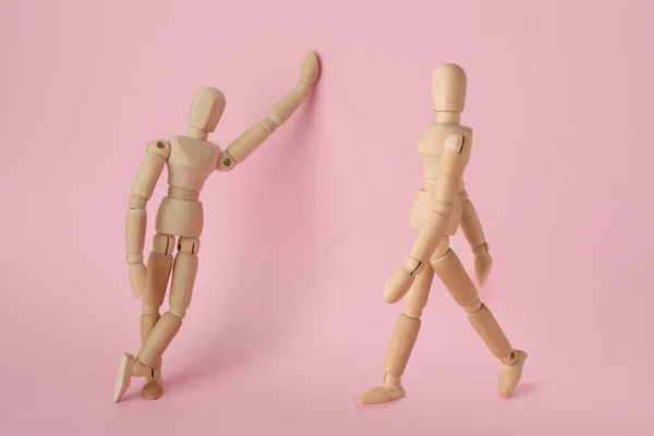 粉色背景下不同姿势的木制人体模型 — 图库照片