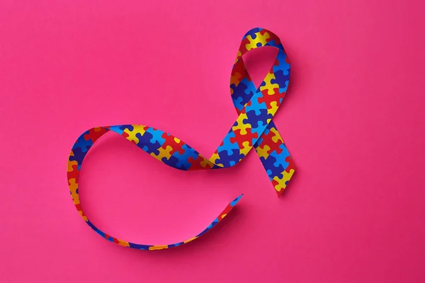 世界自閉症の日 ピンクの背景にカラフルなパズルリボン トップビュー — ストック写真