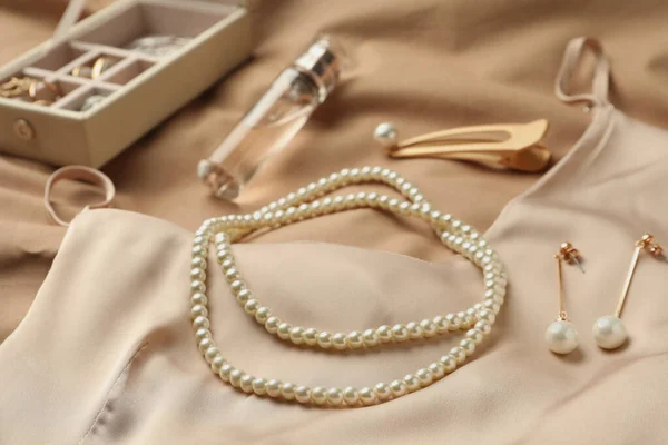 带珍珠的时尚珠宝 米色面料上的奢侈香水和丝绸衣服 — 图库照片