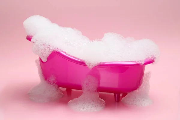 Toy Bathtub Overflowing Foam Pink Background — стоковое фото