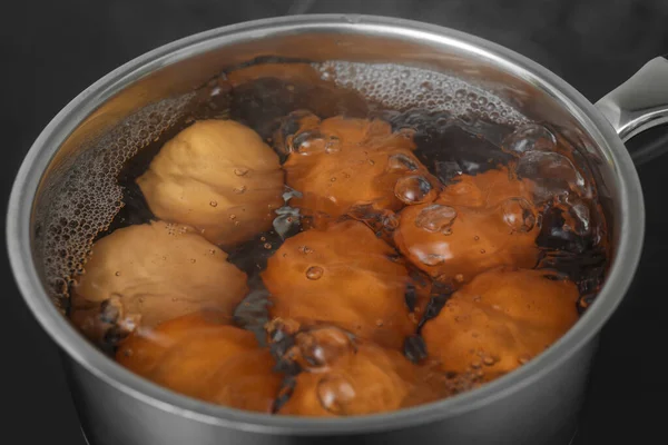 Boiling chicken eggs in saucepan on electric stove, closeup