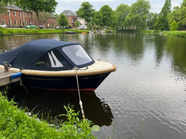 Çevresi yeşilliklerle çevrili rıhtımlı ve demirli tekneyle şehir kanalının güzel manzarası.