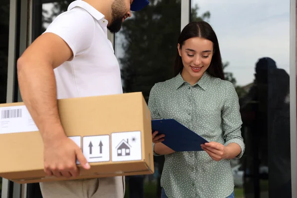Woman Signing Delivered Parcel Entrance Outdoors — Stockfoto