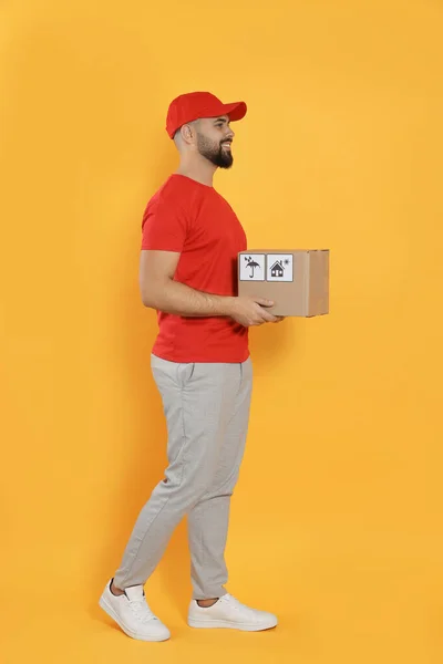 Courier Holding Cardboard Box Yellow Background — Stockfoto