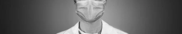 グレーの背景に医療面マスクを身に着けている男のクローズアップビュー バナーデザイン 白黒写真 — ストック写真