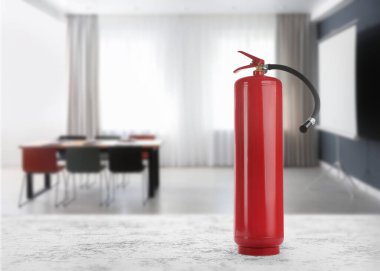 Fire extinguisher on stone table in meeting room. Space for text