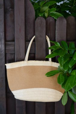 Dışarıdaki ahşap çitlerde asılı şık bir çanta. Plaj aksesuarı