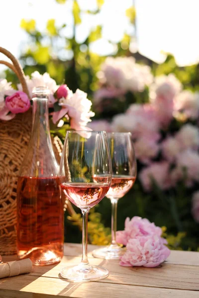 Μπουκάλι Και Ποτήρια Ροζέ Κρασί Κοντά Όμορφες Παιώνιες Ξύλινο Τραπέζι — Φωτογραφία Αρχείου