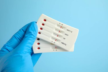 Doktor açık mavi arka planda hepatit için iki adet kullan at ekspres test tutuyor.