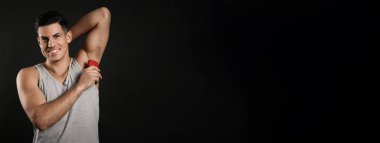 Siyah arka planda deodorant kullanan yakışıklı bir adam, mesaj için yer var. Pankart tasarımı