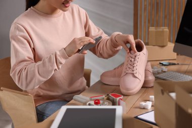 Ofisteki masada pembe spor ayakkabıların fotoğrafını çeken bir satıcı, yakın plan. Çevrimiçi mağaza