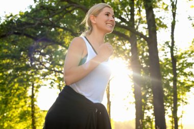 Woman running outdoors in morning, low angle view