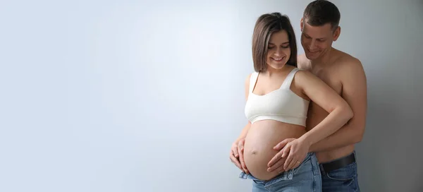 Man Touching His Pregnant Wife Belly Light Background Space Text — ストック写真