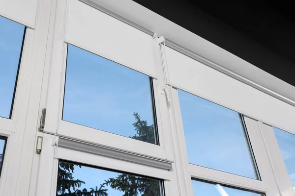 Window with open white roller blinds indoors, low angle view