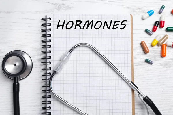 Notebook Word Hormones Stethoscope Pills White Wooden Table Flat Lay — Stock Photo, Image
