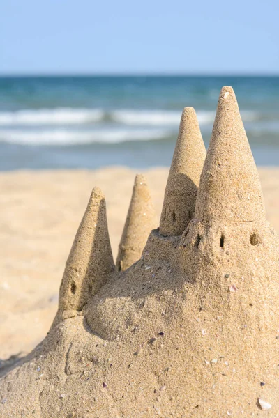 Beach with sand castle near sea on sunny day, closeup