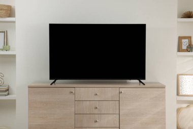 Odanın ahşap dolabında geniş bir televizyon var.