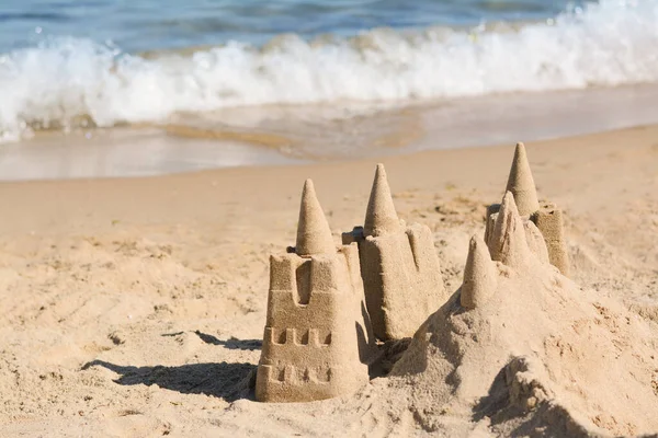 Beach with sand castle near sea on sunny day