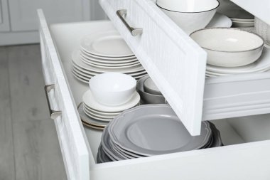 Mutfakta farklı tabak ve kaseleri olan çekmeceleri aç, kapat.