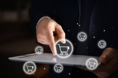 Teslimat konsepti. Çevrimiçi alışveriş için modern tablet kullanan bir adam, kapalı çekim. Pazar arabası çizimleri