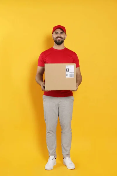 Courier Holding Cardboard Box Yellow Background — Fotografia de Stock