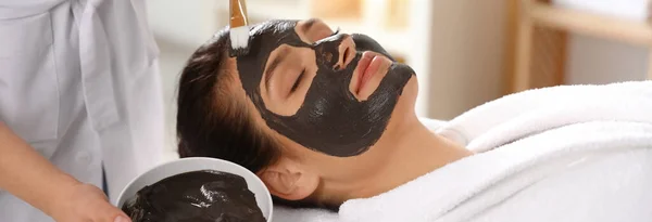 Kosmetolog Nanáší Černou Masku Ženskou Tvář Lázeňském Salonu Návrh Nápisu — Stock fotografie