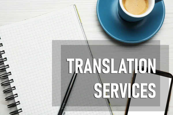 Translation services. Flat lay composition with notebook on white wooden table