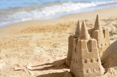 Güneşli bir günde deniz kenarında kumdan kale olan bir sahil. Metin için boşluk