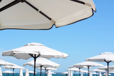 Beautiful white beach umbrellas against blue sky