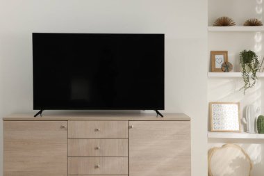 Odanın ahşap dolabında geniş bir televizyon var.