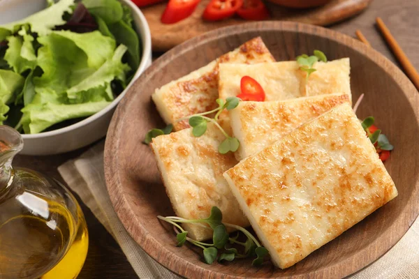 Delicious turnip cake with microgreens on wooden table, closeup