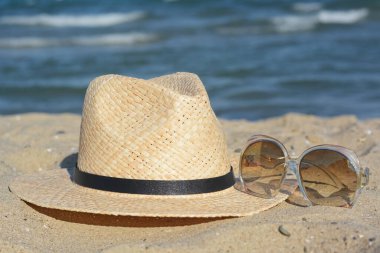 Stil hasır şapka ve güneş gözlüğü kumlu sahilde