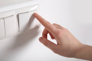 Kapalı mekanda ışığı kapatan kadın, yakın çekim. Enerji tasarrufu kavramı