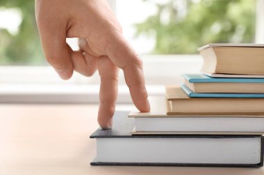 Woman imitating stepping up on books with her fingers indoors, closeup