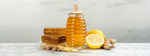 Tasty aromatic honey, lemon and ginger on white marble table. Banner design