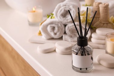 Aromatik kamış oda spreyi ve spa taşları beyaz masada, metin için yer