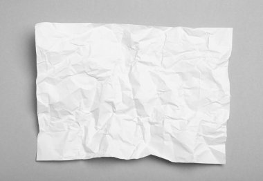 Gri arkaplan üzerine beyaz buruşuk kağıt yaprağı, üst görünüm