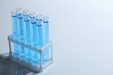 Işık arka planında mavi sıvılı test tüpleri. Metin için boşluk