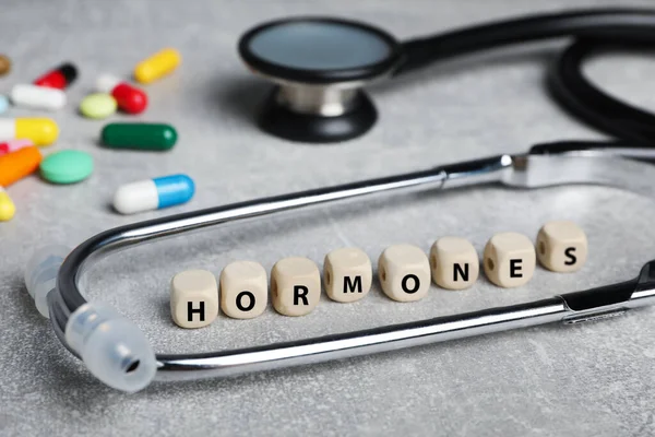 Word Hormones Made Wooden Cubes Stethoscope Pills Grey Table Closeup — Stock Photo, Image