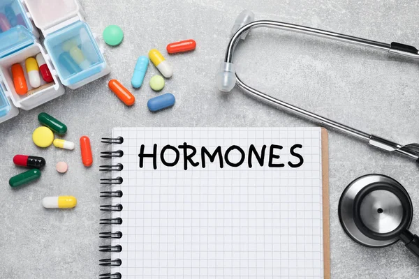 Notebook Word Hormones Stethoscope Pills Grey Table Flat Lay — Stockfoto