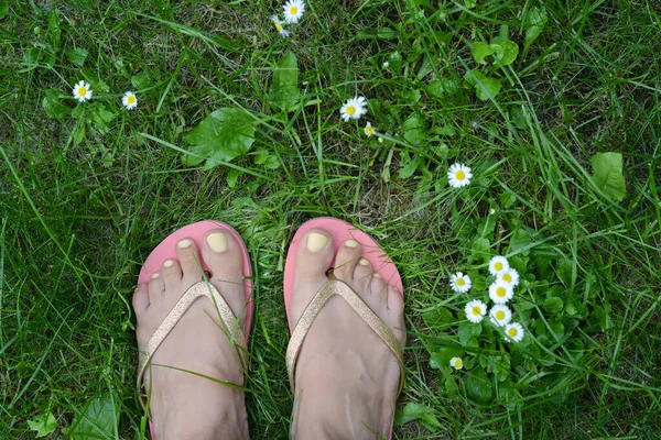 Woman wearing stylish flip flops on green grass outdoors, top view